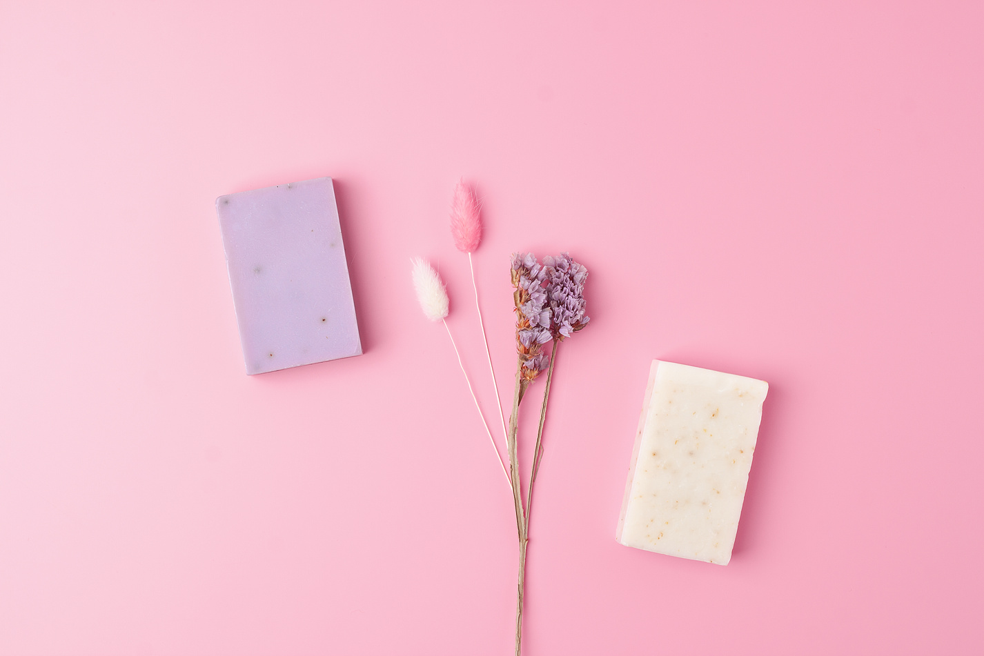 Soap with flowers on pink background. Flat lay, copy space.